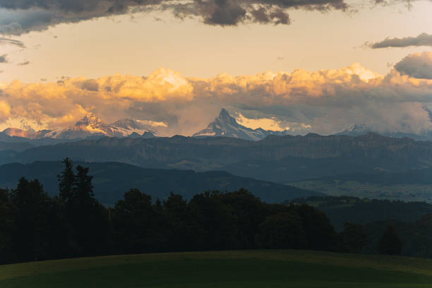 Alpine mountain range and matterhorn peak catching late afternoon golden sunlight through clouds