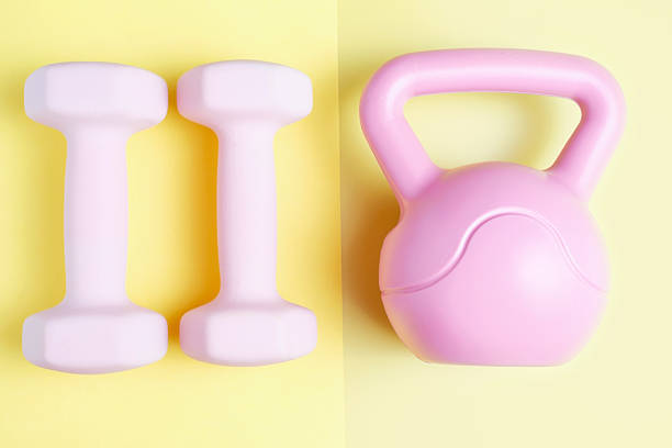 Kettlebell and dumbbells on yellow background close up top view.