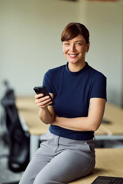 istock Professional Woman Sitting At Office Desk Using Smartphone In A Modern Workspace 2247245452