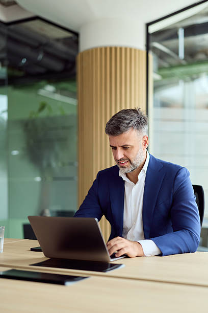 istock Professional Man in Blue Suit Working on Laptop at Modern Open-Plan Office 2247245486