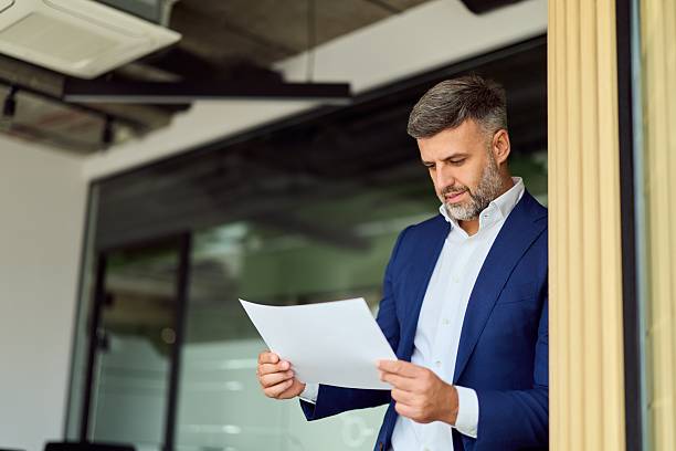 istock Professional Man In Blue Suit Reading A Document In A Modern Office Space 2247245491