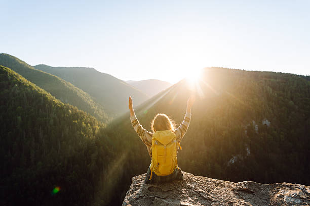 istock Young hiker with yellow hiking backpack standing on cliff at sunset. Real view. 2247245818