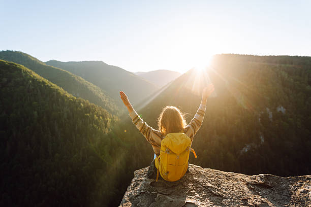 istock Young hiker with yellow hiking backpack standing on cliff at sunset. Real view. 2247245976