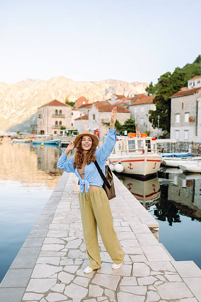 istock Beautiful tourist in a hat and with a backpack strolls along the pier at dawn. 2247247636