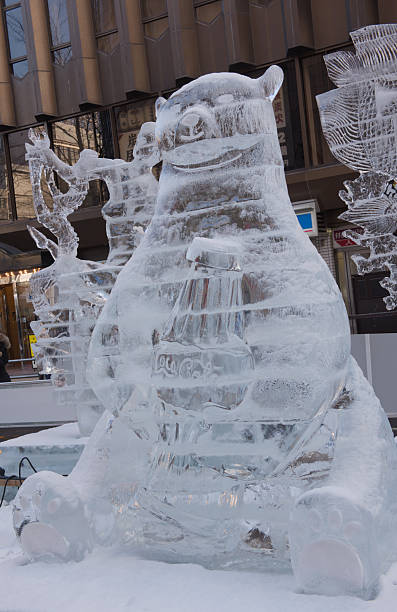 Sapporo Snow Festival, Hokkaido, Japan, Feb 06, 2016: An ice sculpture of a bear holding a Coca-Cola bottle displayed outdoors on a snow-covered base during the daytime.