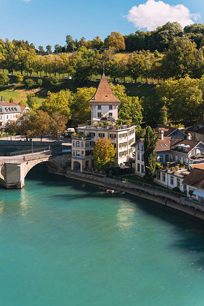 Historic buildings along the turquoise aare river in bern, switzerland, with green hillside