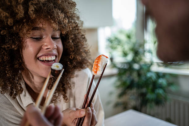 Happy couple enjoying sushi lunch with chopsticks