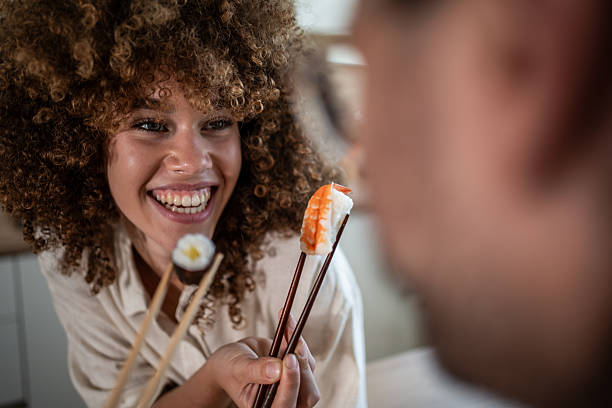 istock Woman sharing sushi with partner during cheerful date 2247255085