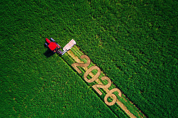 Aerial View Of Farmland Field with Working Red Tractor And Text 2026 Markings In Crops Agro background stock photo
