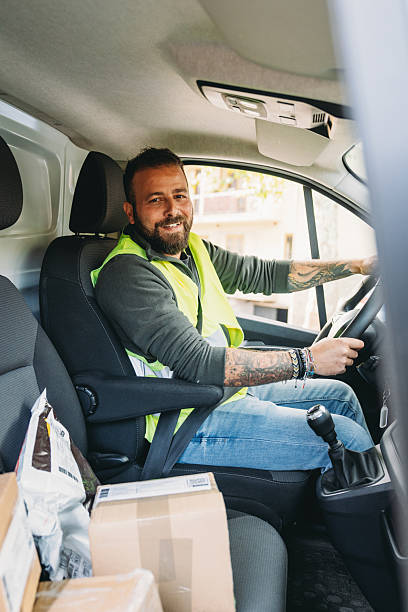 istock Smiling delivery man sitting in van with packages 2247258887