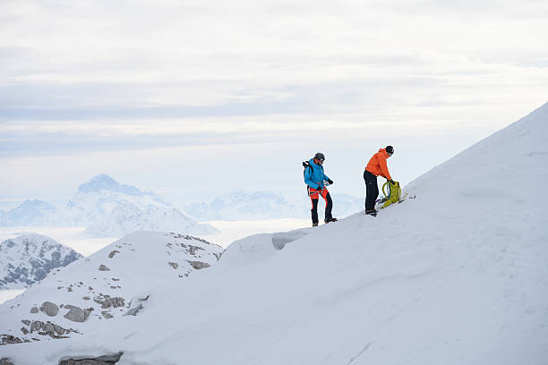 istock Mountaineers Taking a Break on Snowy Slope with Misty Mountain Range in Sight 2247264109
