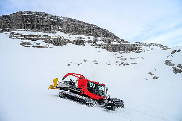 snowcat ratrack with snowplow,snow grooming machine,remover truck preparing ski slope,piste,hill at alpine skiing winter resort. Heavy machinery,tractor mountain equipment track vehicle.