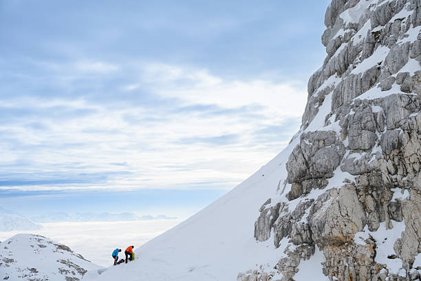istock Winter Mountaineers Pausing on Snowy Slope with Misty Mountain Range in View 2247264120