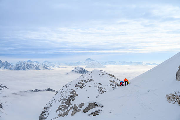 istock Mountaineers Pause on Snowy Slope, Taking in Misty Mountain Range 2247264187