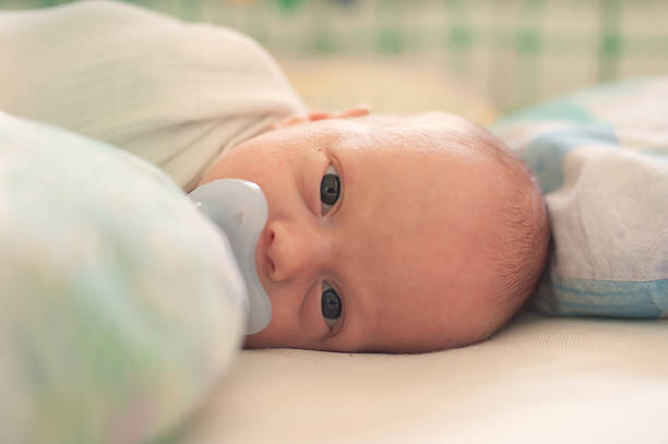 istock Newborn baby lying in crib with pacifier during day, calm and peaceful 2247264939