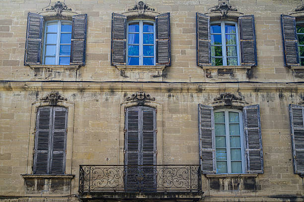 Building facade with shutters and balcony in the city of Avigon in the Vaucluse department in the Provence-Alpes-Côte d'Azur region of southeastern France. Located on the left bank of the river Rhône. Avignon is also known as 'La Cité des Papes' (The City of the Popes). Avignon is also known as 'La Cité des Papes' (The City of the Popes)
