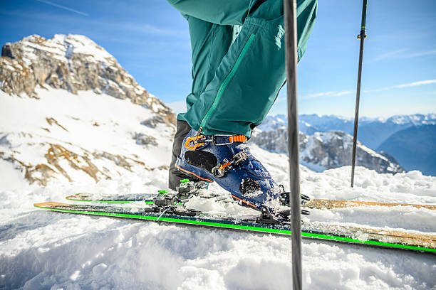 istock Skier Fastening Skis on Snowy Mountain Under Clear Blue Sky 2247267304