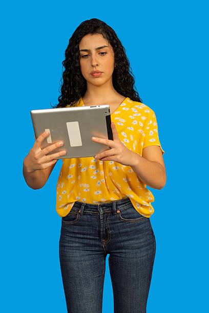 istock Young woman engrossed in digital tablet on blue background 2247267641