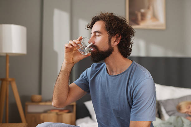 istock Man drinking fresh water in bedroom in morning 2247268771