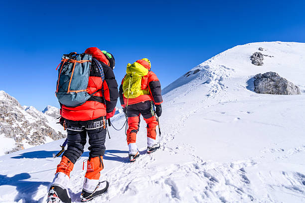 istock Determined Mountaineers Climbing Snowy High Mountain Peaks Under Bright Blue Sky 2247270506