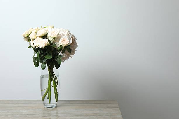 Beautiful bouquet of fresh flowers in vase on chest of drawers indoors