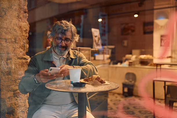 istock Mature adult man using smartphone in cafe 2247273674