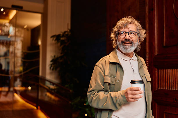 istock Smiling senior man holding coffee cup in hotel lobby 2247277020