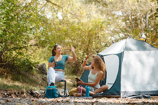istock Two friends enjoying a relaxed moment by their tent in a serene forest setting during a sunny day, sharing stories and laughter in nature 2247277065