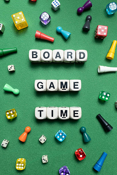 istock 'Board Game Time' spelt with wooden dice over a green background. 2247279844
