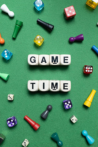 istock 'Game Time' spelt with wooden dice over a green fabric baize. 2247279874