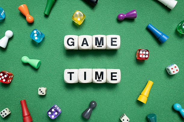 istock 'Game Time' spelt with wooden dice over a green fabric background. 2247279892