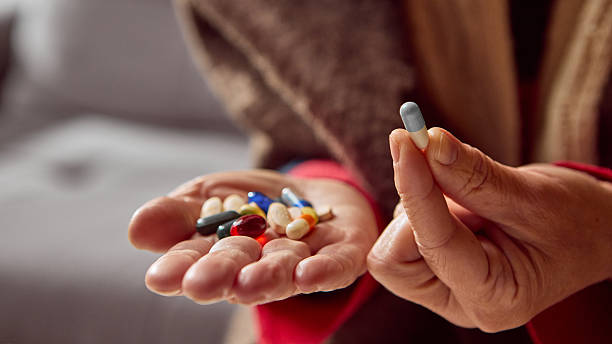 istock Elderly woman holding single capsule with pills on palm for selection 2247280719