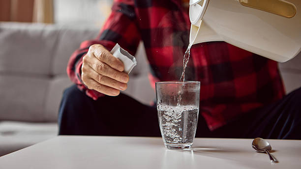istock Senior man pouring hot water into glass while preparing powdered medicine drink 2247280726