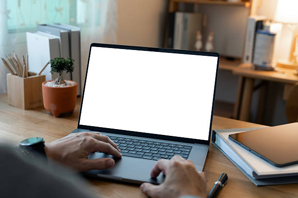 istock Close-up of a man working on a laptop with a blank white screen mockup, ideal for demonstrating websites or applications in a modern home office setting. 2247281545