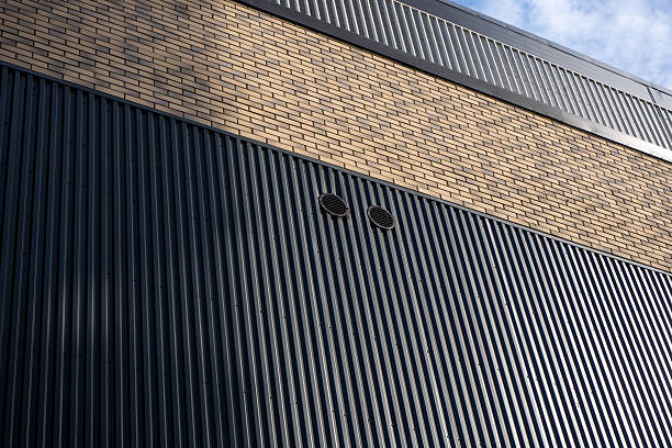 istock Industrial building facade with corrugated metal cladding and brick detail, combination of textures and materials. For architecture, industrial design, construction, facade materials. Real photo 2247281631