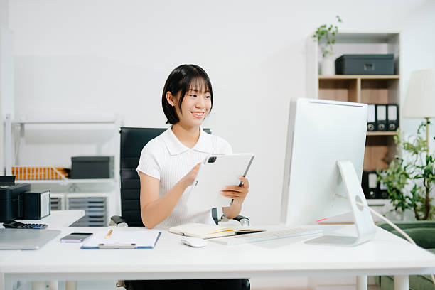 istock Confident Asian woman with a smile standing holding notepad and tablet at the modern office. 2247281934