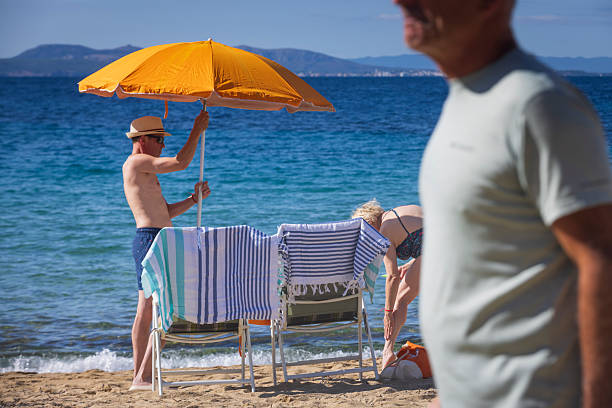 Roses, Spain - September 9, 2024: older couple settles on the beach near the Spanish seaside resort of Roses