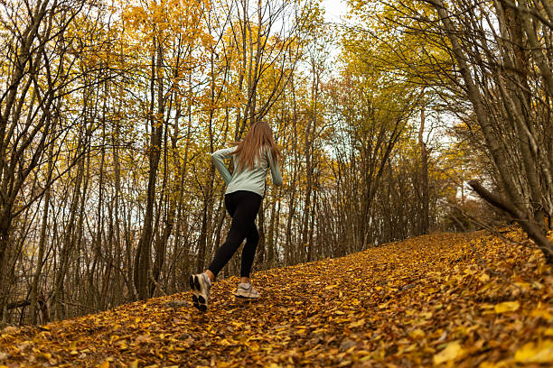 Rear view of a woman running uphill in a forest