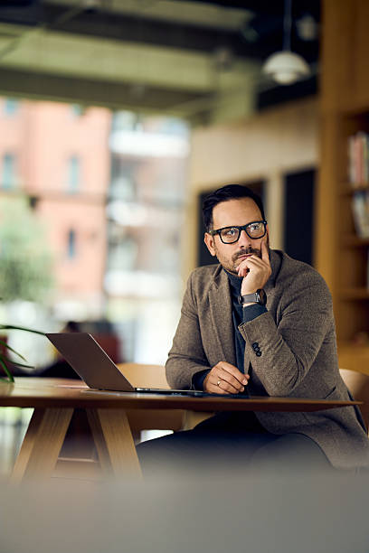 istock Thoughtful Professional Man In Brown Blazer At Modern Office Desk With Laptop 2247285048
