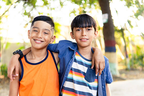 istock Two young hispanic boys smiling, embracing friendship outdoors 2247287961