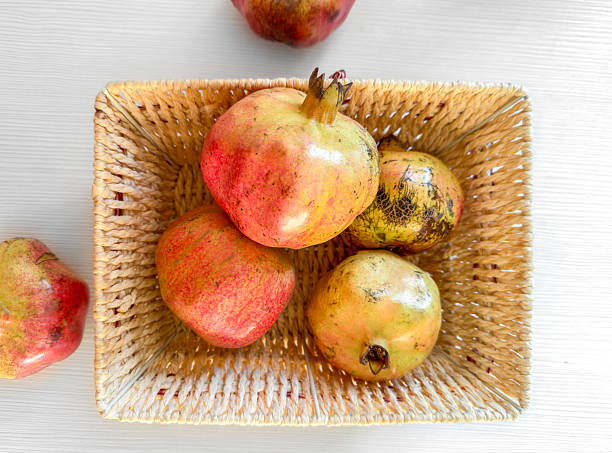 istock Imperfect Pomegranates in a Woven Basket on Light Background, Top View, flat lay 2247293632