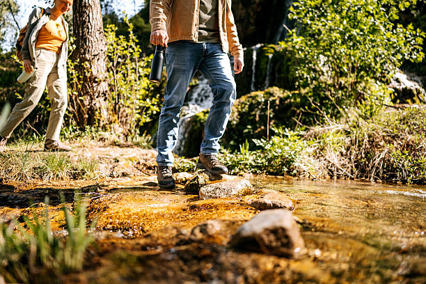 istock Close up shot of couple crossing stream together while smiling 2247295885