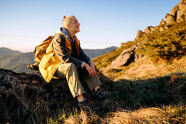 istock Female hiker sitting on rock during mountain adventure 2247296119