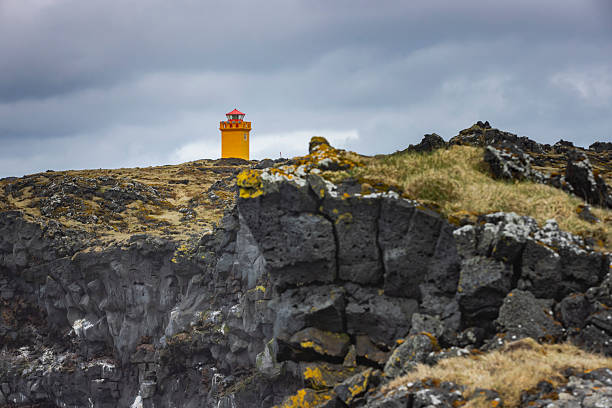 characteristic orange lighthouse at Svortuloft, a 4-kilometer-long coastal cliff located on the westernmost point of the Snæfellsnes peninsula in West Iceland; Svortuloft, Iceland