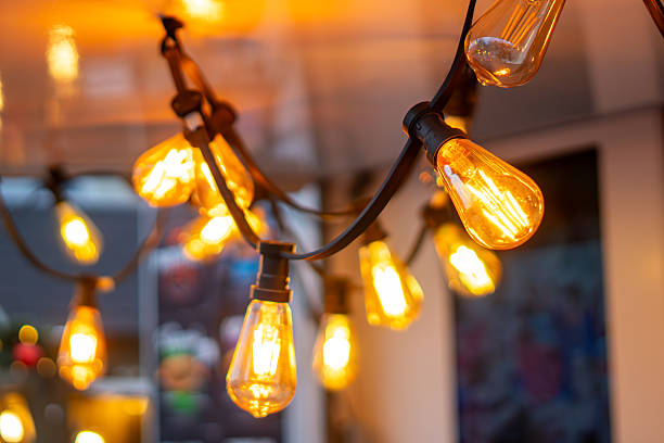 istock Warm decorative bulbs on a black cable above a Christmas market stand, creating glowing ambience with softly blurred surroundings in the background. 2247296374