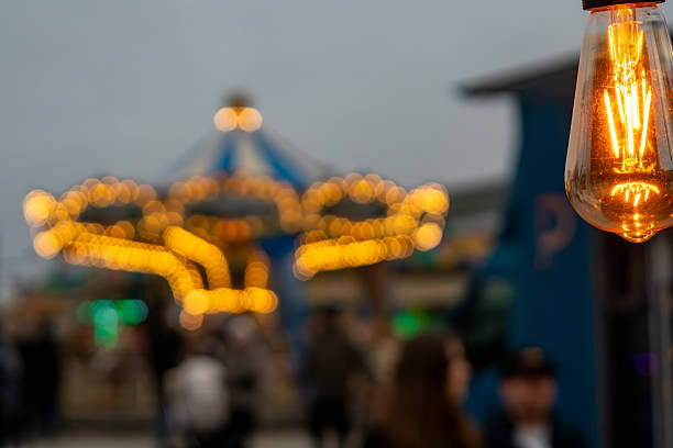 Decorative bulb at a Christmas market with a blurred carousel in the background, creating festive ambience and striking holiday bokeh lighting effects.