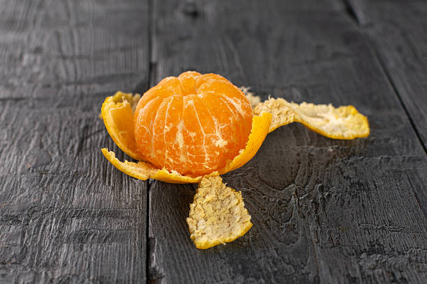 istock Freshly Peeled Mandarin Orange on Rustic Dark Wooden Surface 2247297275