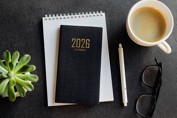 istock Stylish Desk Setup With 2026 Planner, Notebook, Pencil, Glasses, and Coffee on Wooden Surface 2247299109