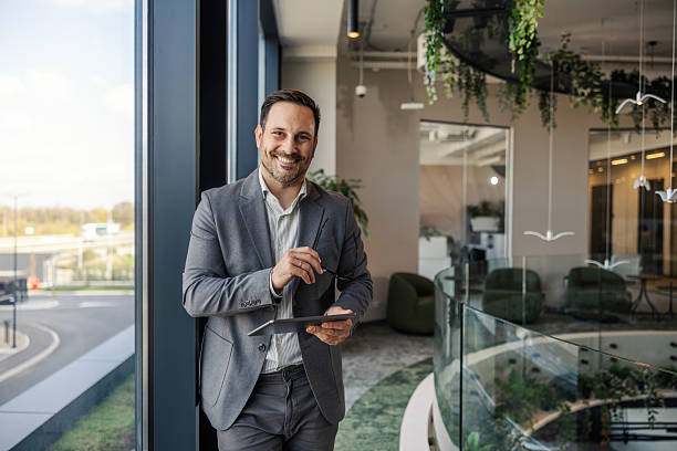 istock Confident businessman standing in modern office holding tablet 2247299297