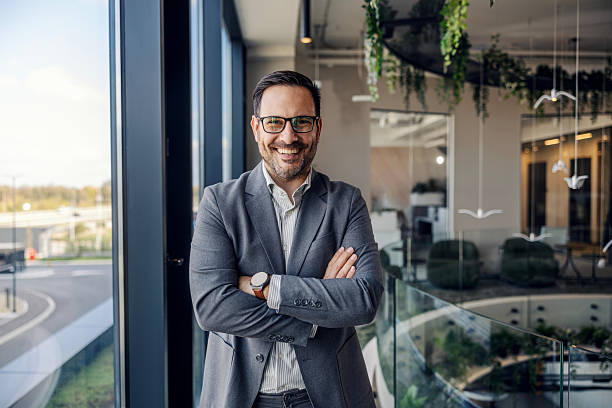 istock Smiling confident businessman standing with arms crossed in modern office 2247299347